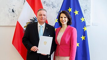 Ein Mann und eine Frau stehen nebeneinander und halten ein Dokument in den Händen.