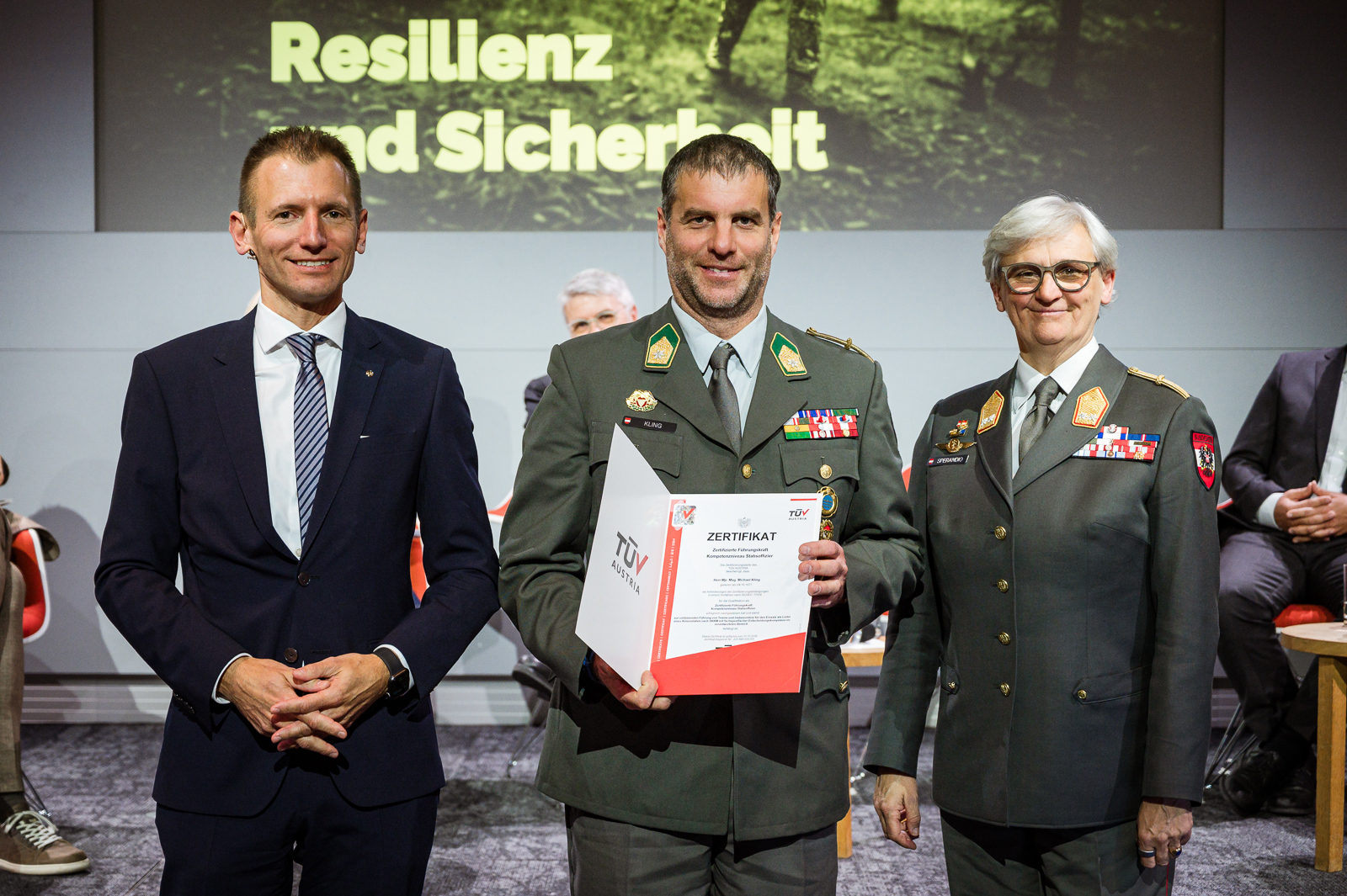 <br /> Drei Personen bei Zertifikatsübergabe.