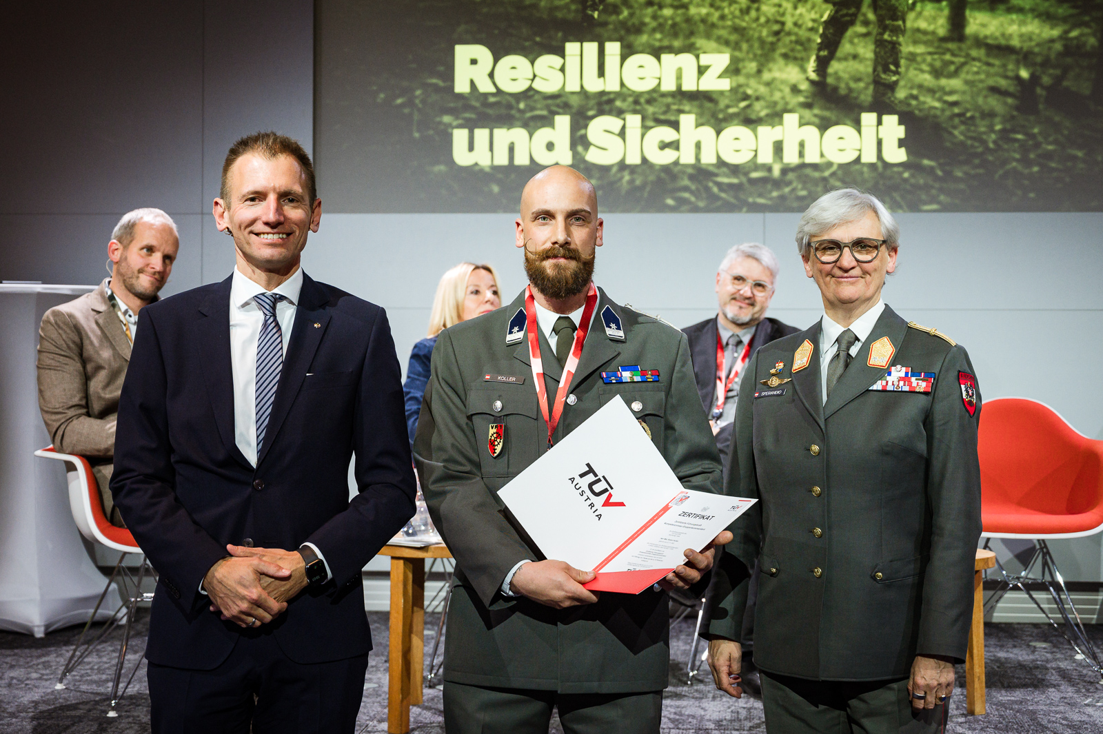 <br /> Drei Personen bei Zertifikatsübergabe.