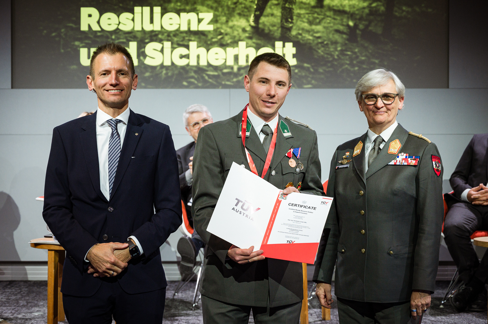 <br /> Drei Personen bei Zertifikatsübergabe.